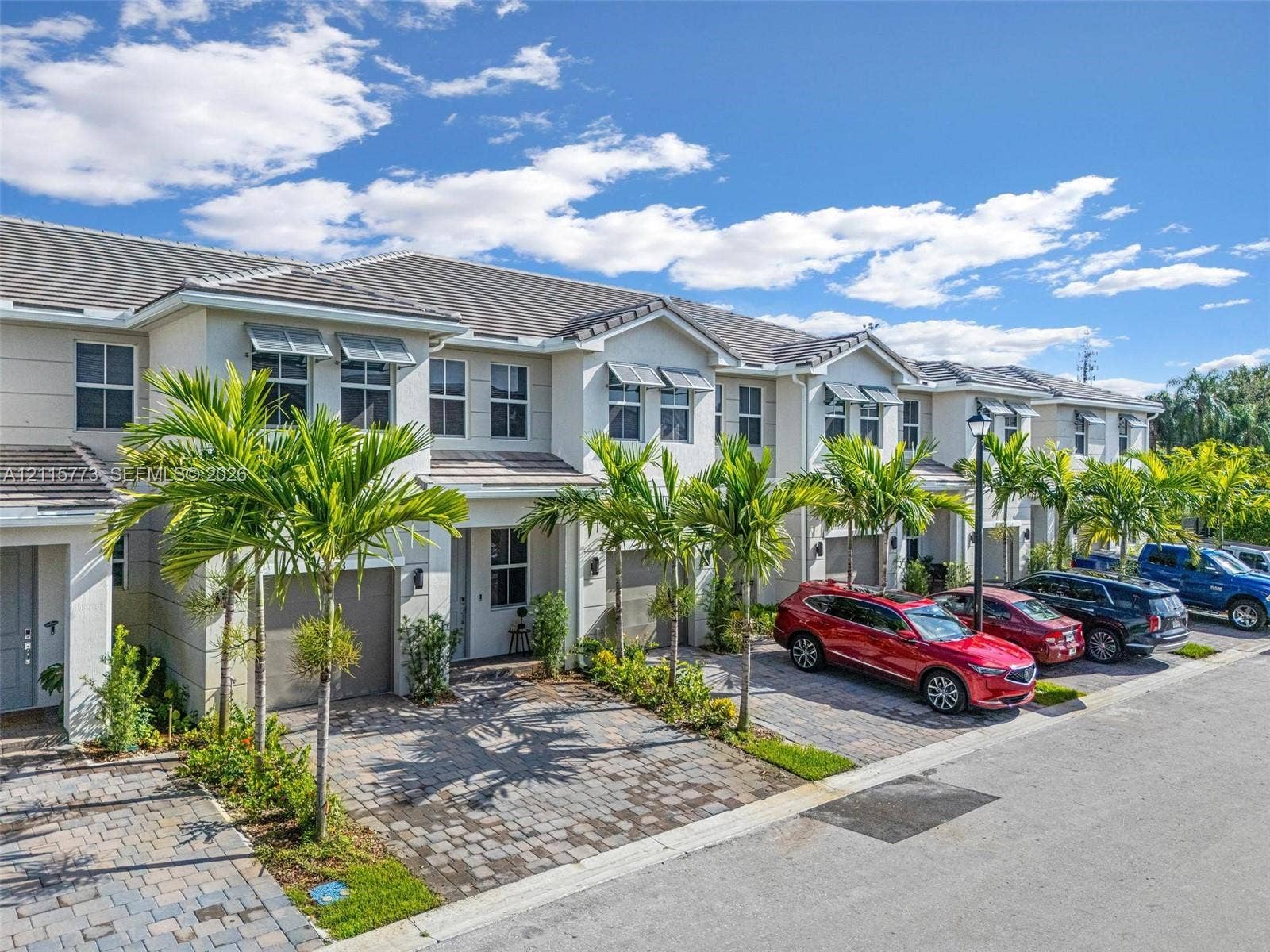 17033 SW 1st Street, #1, Pembroke Pines, Pembroke Pines, FL 33027 Multi-unit residential exterior featuring a light-toned stucco faade, shingle roofing, integrated garage doors, and paver driveways lined with palm trees