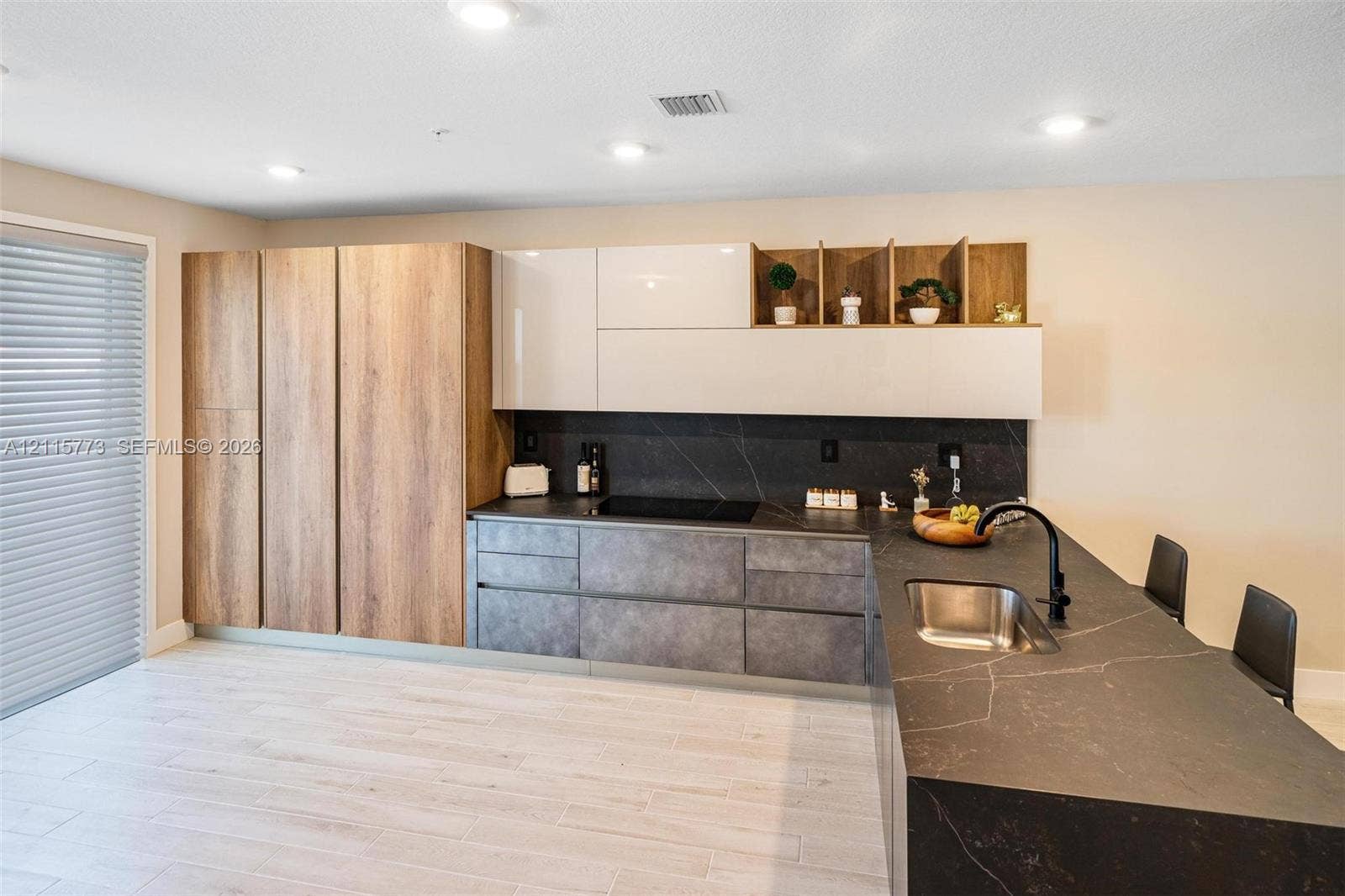 17033 SW 1st Street, #1, Pembroke Pines, Pembroke Pines, FL 33027 Kitchen featuring flat-panel wood-finish cabinetry, gloss-finish upper cabinets, stone-surfaced countertops, integrated sink with matte black faucet, and stone-surfaced backsplash