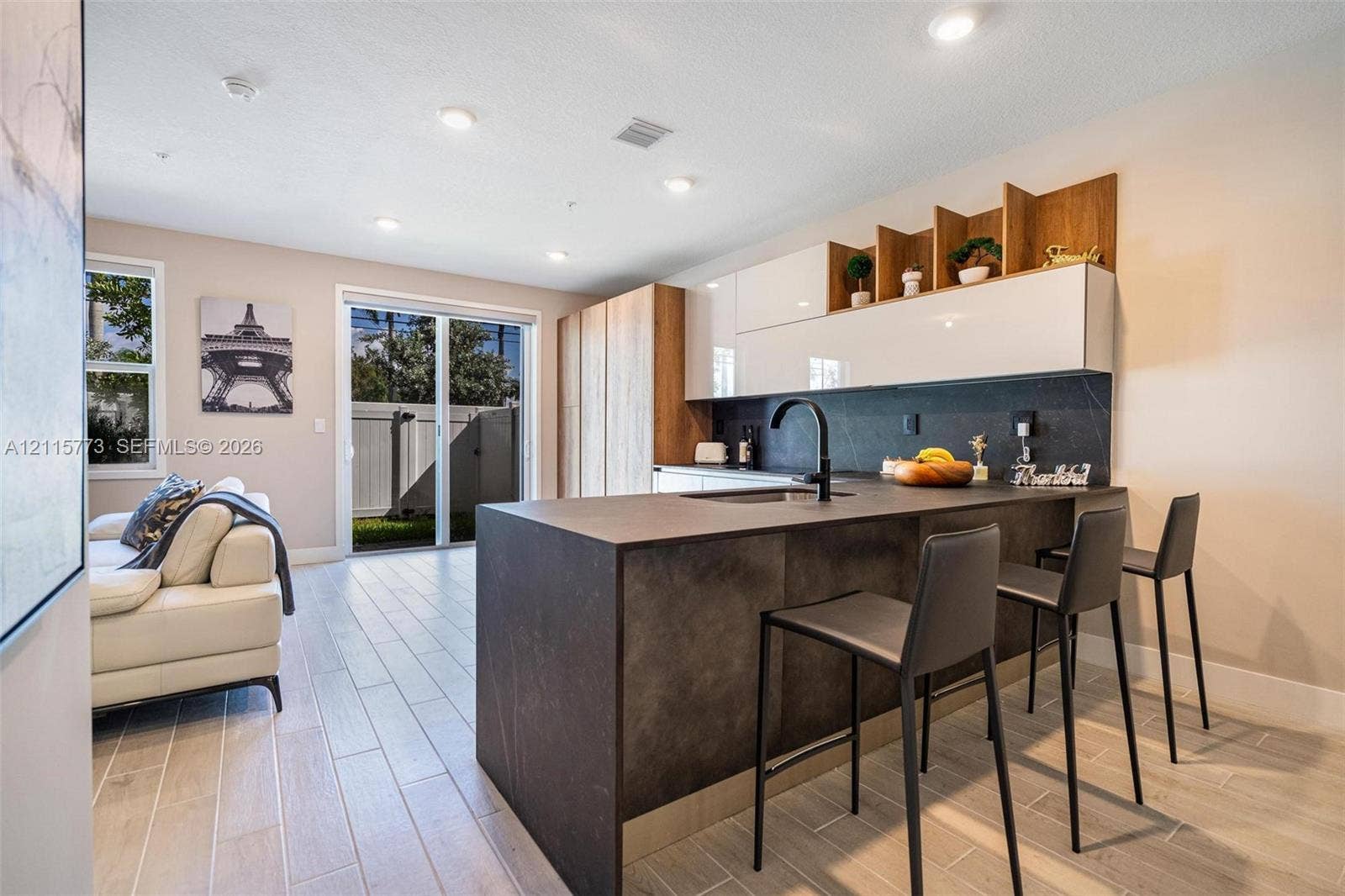 17033 SW 1st Street, #1, Pembroke Pines, Pembroke Pines, FL 33027 Kitchen featuring a waterfall-edge island with matte dark countertops, two-tone cabinetry, recessed lighting, and wood-finish flooring throughout