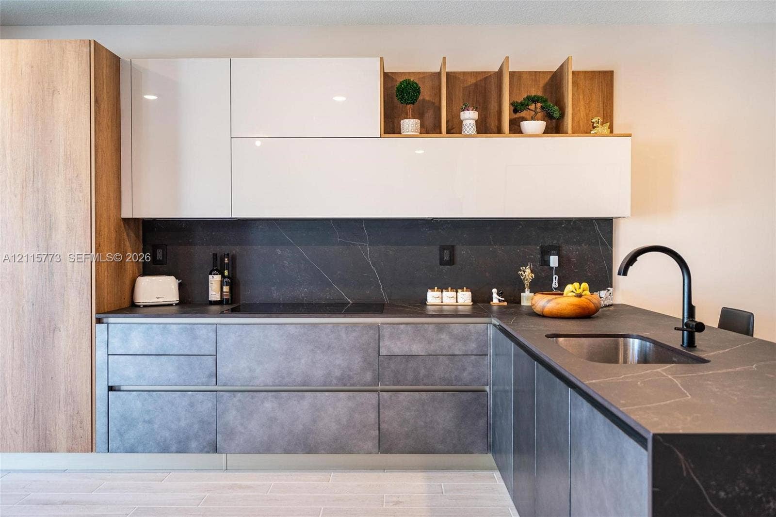 17033 SW 1st Street, #1, Pembroke Pines, Pembroke Pines, FL 33027 Modern kitchen featuring high-gloss white upper cabinetry, wood-finish accent shelving, textured matte lower cabinetry, dark stone-finish countertops with integrated backsplash, and a matte black gooseneck faucet