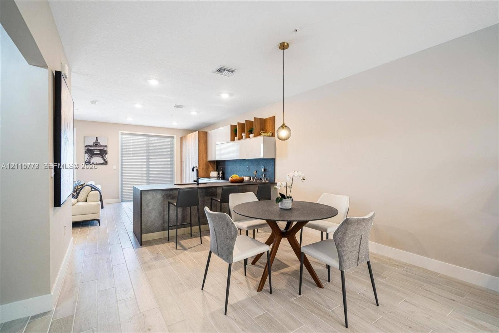 17033 SW 1st Street, #1, Pembroke Pines, Pembroke Pines, FL 33027 Kitchen featuring an island with a dark textured finish, light-toned flat-panel cabinetry, open shelving, tile flooring, and a modern pendant light fixture