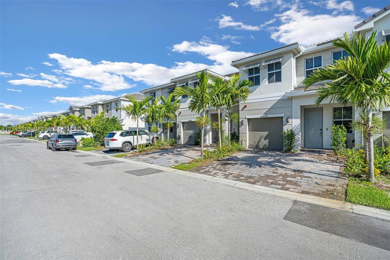 17033 SW 1st Street, #1, Pembroke Pines, Pembroke Pines, FL 33027 Two-story townhome exterior featuring a stucco facade, paver driveway, single-car garage, and integrated landscaping with mature palm trees