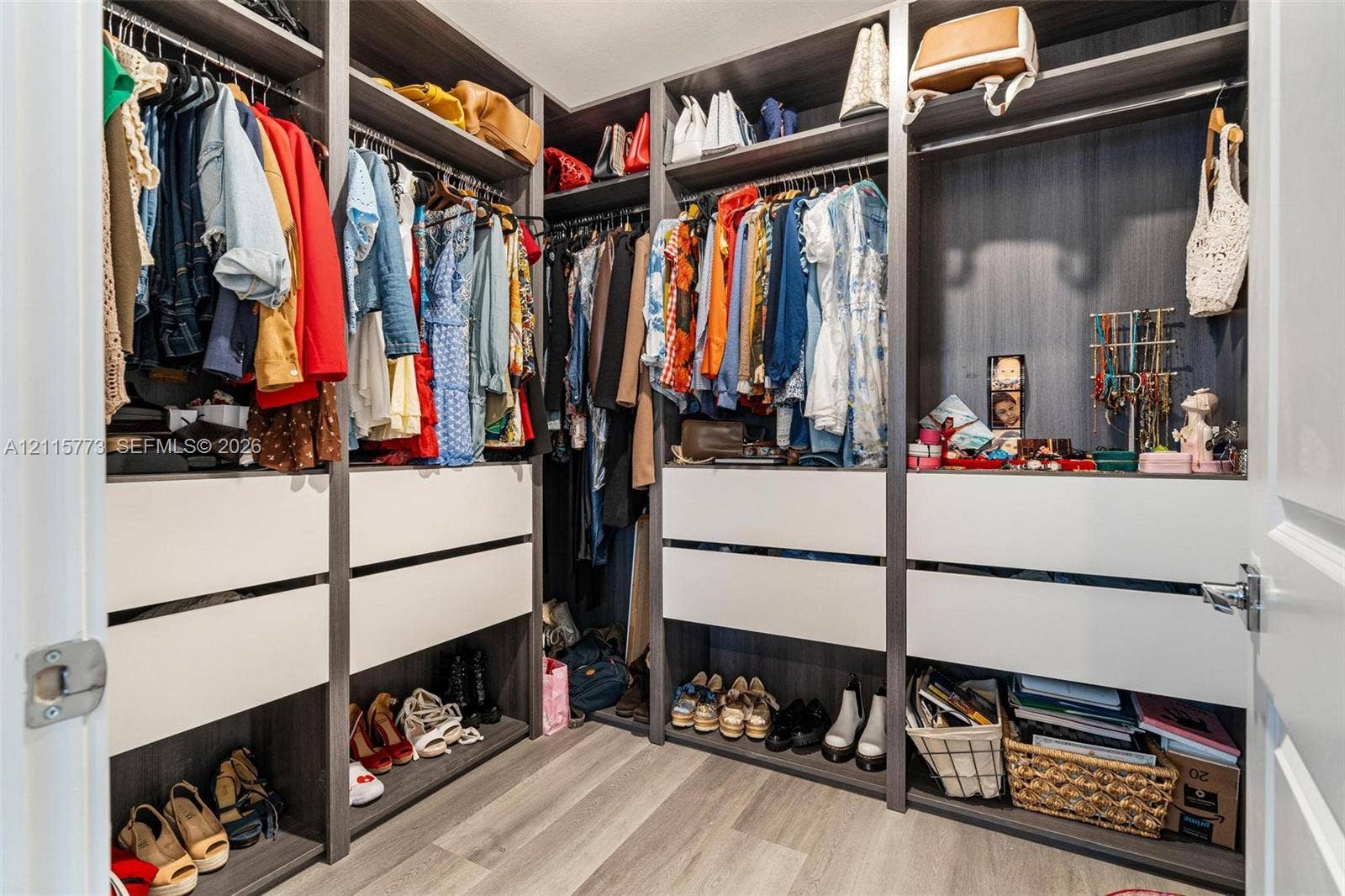 17033 SW 1st Street, #1, Pembroke Pines, Pembroke Pines, FL 33027 Walk-in closet featuring multi-tiered shelving, built-in drawer units with matte white faces, integrated hanging rods, and wood-finish flooring