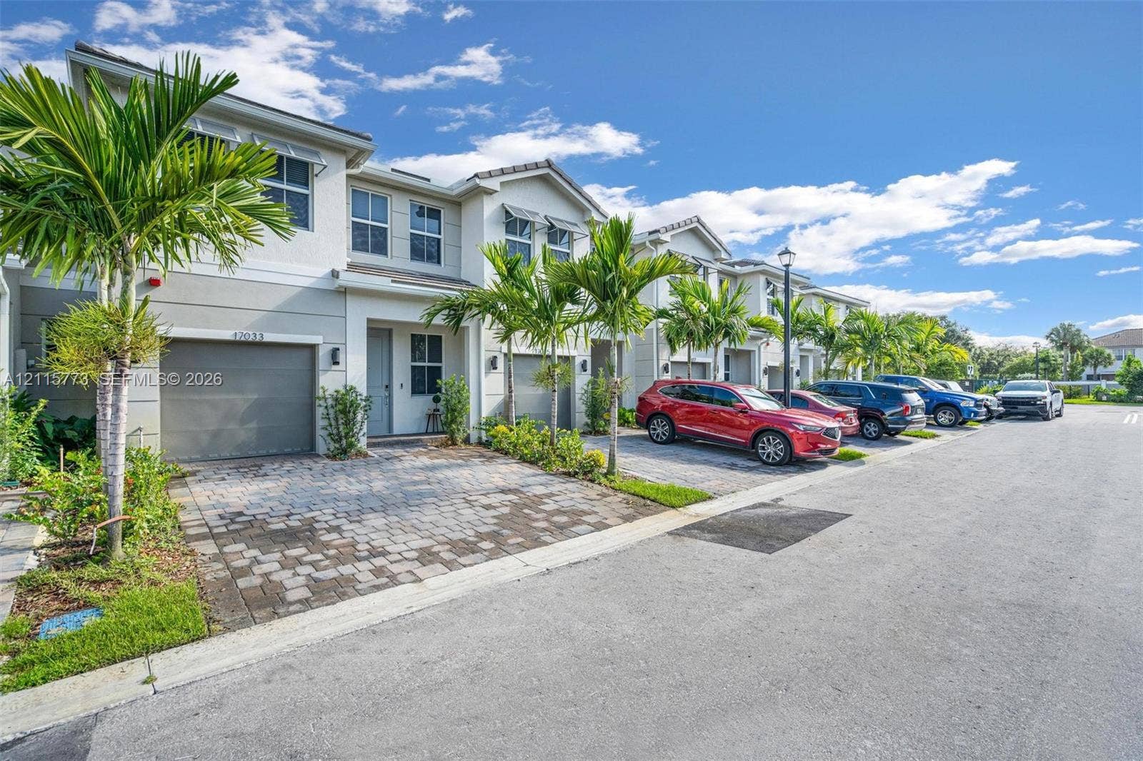 17033 SW 1st Street, #1, Pembroke Pines, Pembroke Pines, FL 33027 Multi-story townhome exterior featuring a stucco facade, paver driveway, attached garage, and metal window awnings