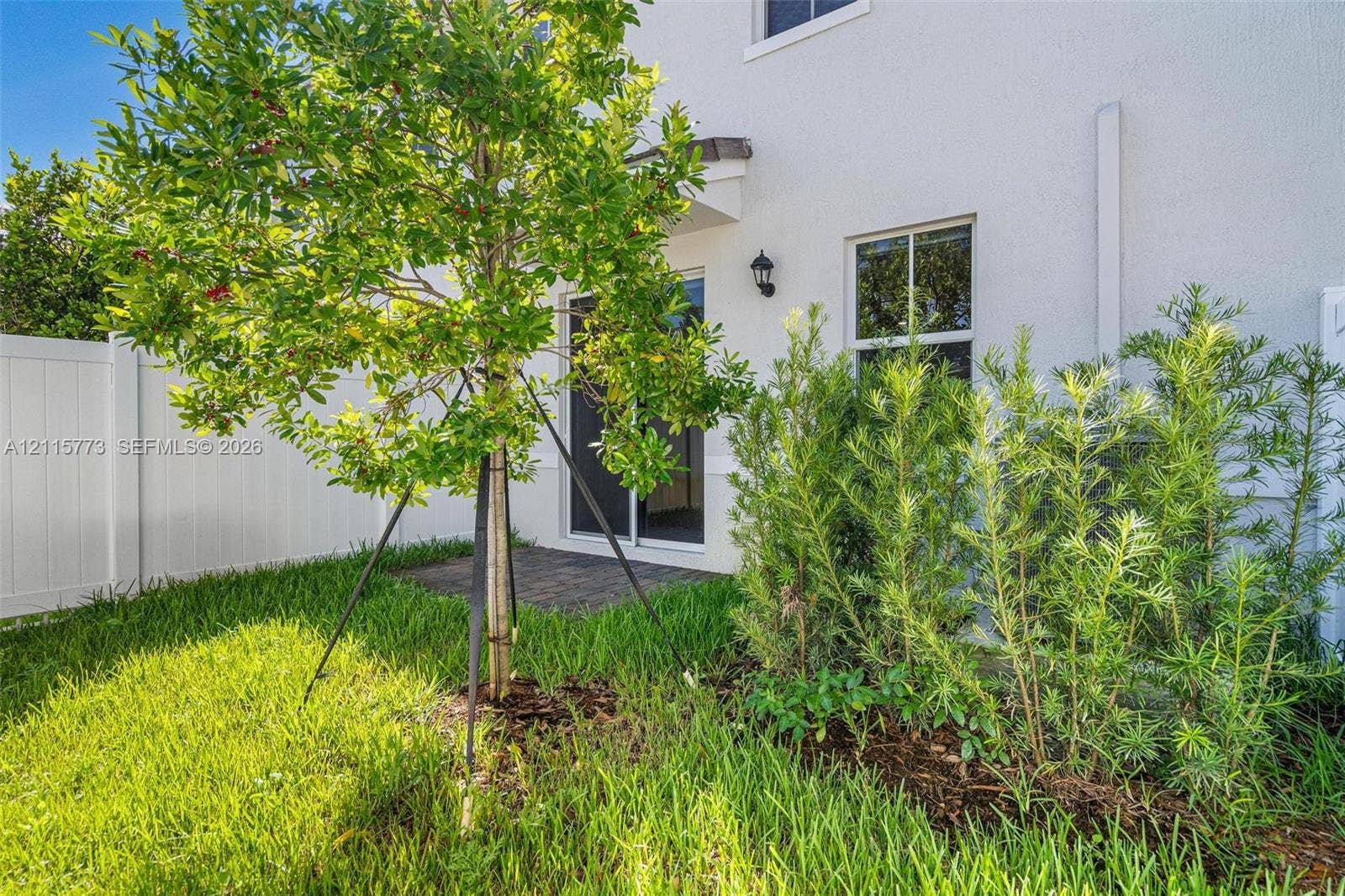 17033 SW 1st Street, #1, Pembroke Pines, Pembroke Pines, FL 33027 Private outdoor space featuring a paved patio, white vinyl privacy fencing, landscaped garden beds, and manicured lawn