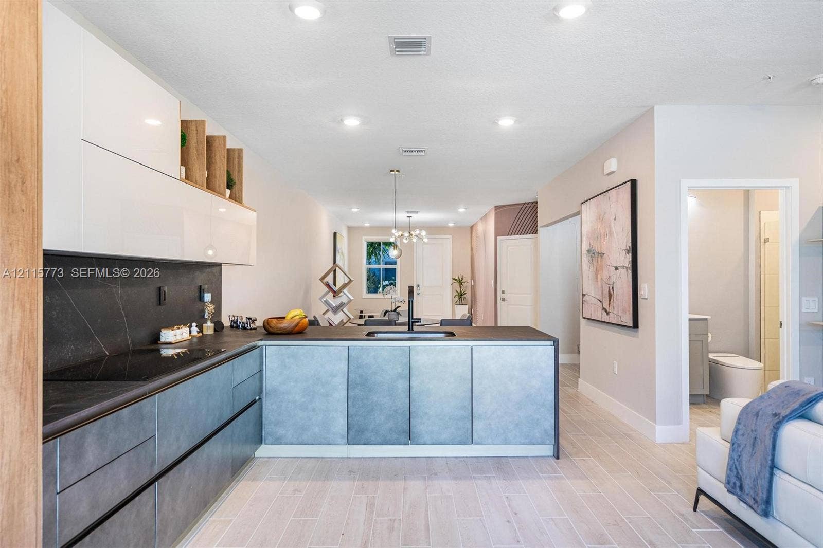 17033 SW 1st Street, #1, Pembroke Pines, Pembroke Pines, FL 33027 Contemporary kitchen featuring white high-gloss upper cabinetry, dark stone-finish countertops, grey lower cabinetry, integrated black hardware, and wood-finish flooring
