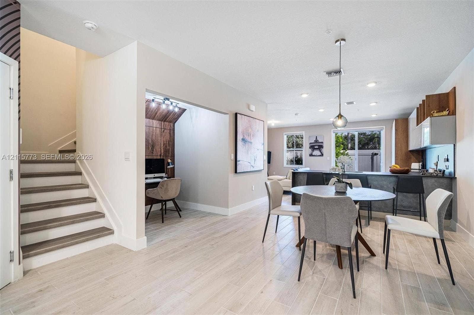 17033 SW 1st Street, #1, Pembroke Pines, Pembroke Pines, FL 33027 Open-concept interior featuring wood-finish flooring, a built-in wood-accented workspace, recessed lighting, and a kitchen island with stone-surface detailing