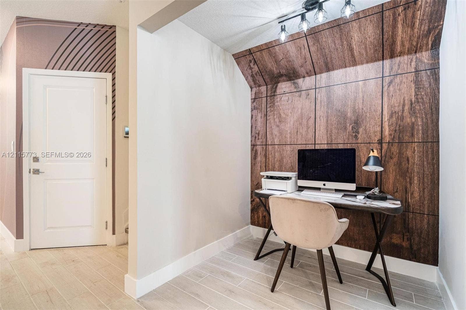 17033 SW 1st Street, #1, Pembroke Pines, Pembroke Pines, FL 33027 Alcove featuring wood-paneled accent wall, light-toned wood-finish flooring, custom geometric mural, and track lighting