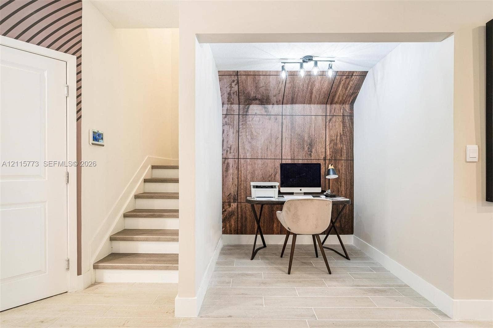 17033 SW 1st Street, #1, Pembroke Pines, Pembroke Pines, FL 33027 Recessed alcove featuring wood-panel accent wall, tile flooring, and multi-bulb track lighting, positioned near a staircase with wood-finish steps