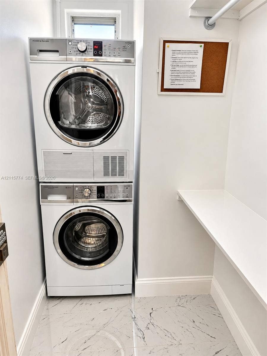 1455 Michigan Avenue, #19A, Miami Beach, Miami Beach, FL 33139 Stacked white front-load washer and dryer, built-in wall shelf, overhead clothing rod, and polished stone-finish floor tiling