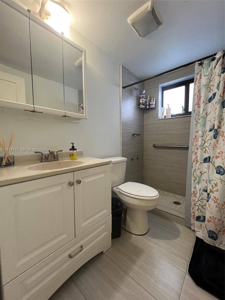 479 E 13th Street, #479, Hialeah, Hialeah, FL 33010 White cabinetry with integrated vanity top and undermount sink, mirrored medicine cabinet, neutral large-format floor tiling, and walk-in shower featuring horizontal tile surround and metal grab bar