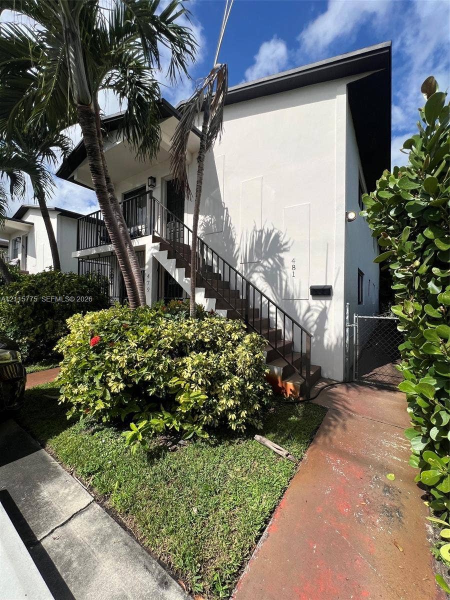 479 E 13th Street, #479, Hialeah, Hialeah, FL 33010 Two-story exterior featuring smooth stucco siding, black metal railings, an open-air staircase, and a concrete walkway
