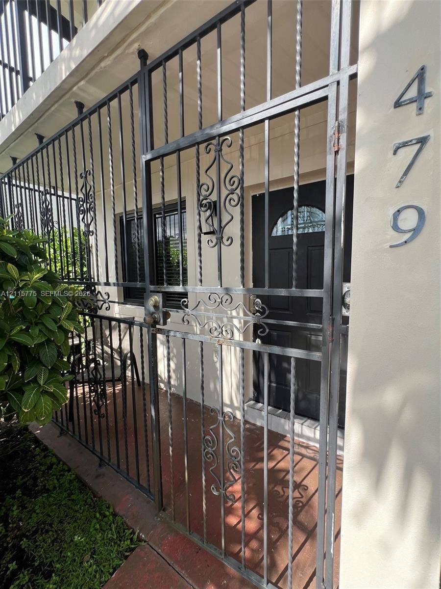 479 E 13th Street, #479, Hialeah, Hialeah, FL 33010 Exterior entryway featuring a black metal security gate with scrollwork detailing, a solid-panel door with a semi-circular glass insert, and mounted house numbers