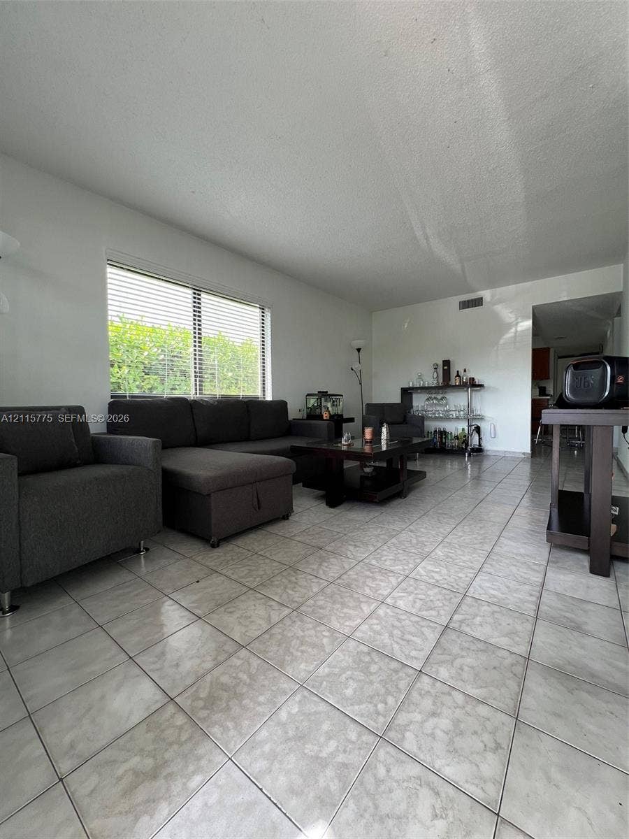 479 E 13th Street, #479, Hialeah, Hialeah, FL 33010 Living area featuring large-format tile flooring, neutral wall paint, and a wide window with integrated blinds