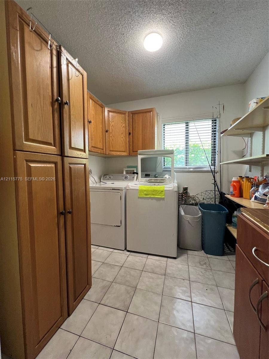 479 E 13th Street, #479, Hialeah, Hialeah, FL 33010 Laundry room featuring tile flooring, wood-finish cabinetry, built-in shelving, and a horizontal window
