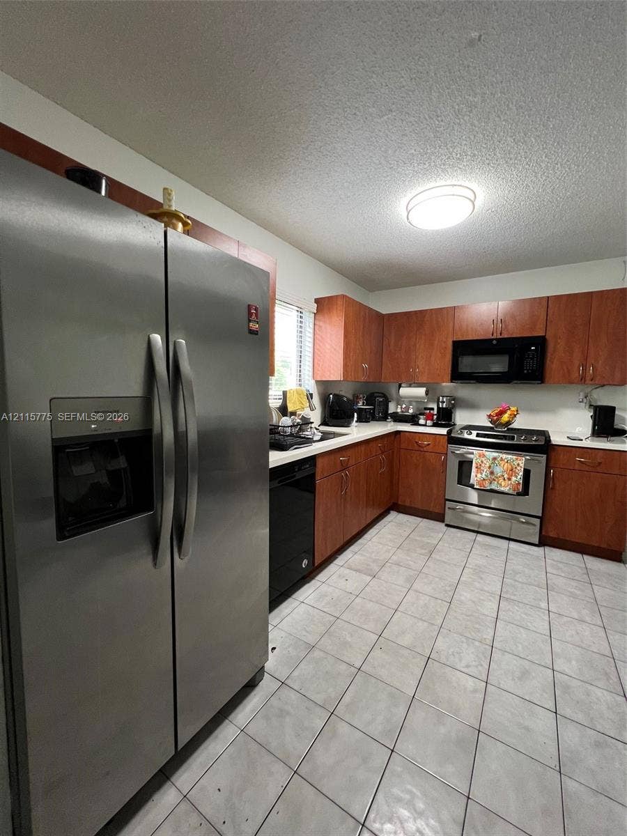 479 E 13th Street, #479, Hialeah, Hialeah, FL 33010 Kitchen featuring wood-finish cabinetry, stainless steel refrigerator, built-in microwave, stainless steel range, and tile flooring