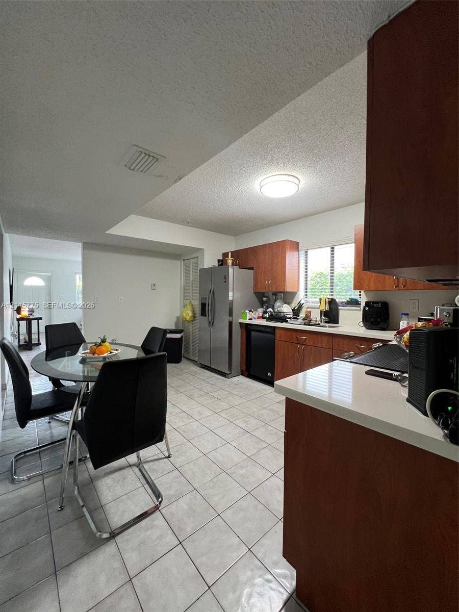 479 E 13th Street, #479, Hialeah, Hialeah, FL 33010 Kitchen featuring wood-finish cabinetry, solid surface countertops, stainless steel side-by-side refrigerator, under-cabinet lighting, and ceramic tile flooring