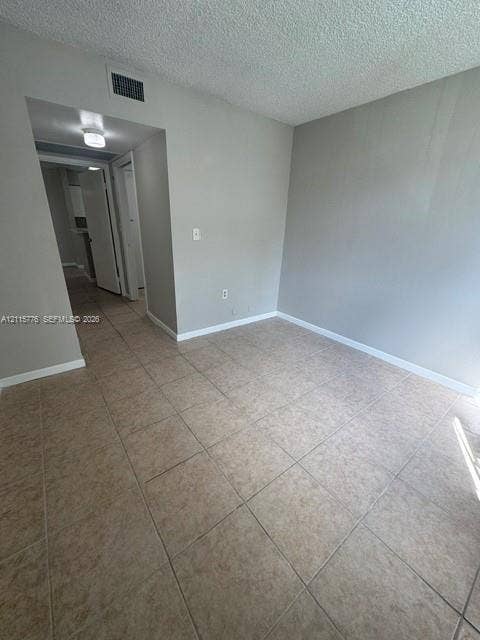 Neutral-toned interior featuring large-format ceramic floor tiling, textured ceiling finish, and recessed overhead lighting