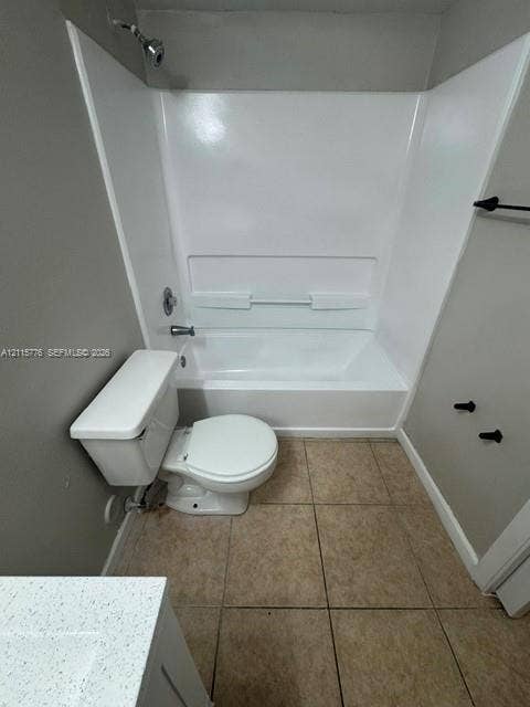Bathroom featuring a white acrylic tub-shower surround, tile flooring, white porcelain toilet, and a vanity topped with a speckled white countertop