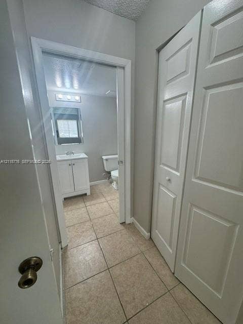 Ceramic tile flooring, white shaker-style vanity cabinet, tri-light fixture, and bi-fold closet doors