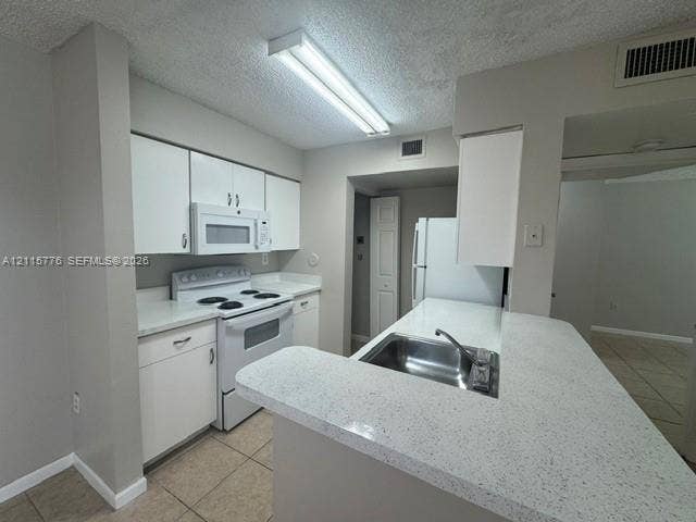 Kitchen featuring white cabinetry, solid-surface countertops, tile flooring, and built-in appliances