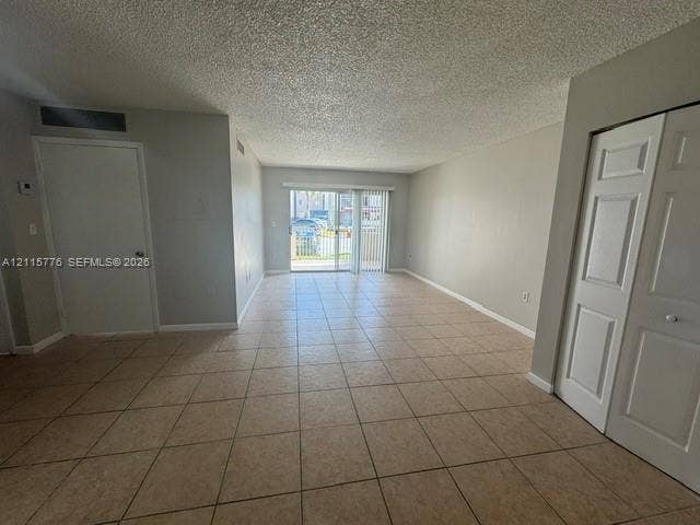 Neutral-toned interior featuring ceramic tile flooring, sliding glass door, and closet with six-panel doors