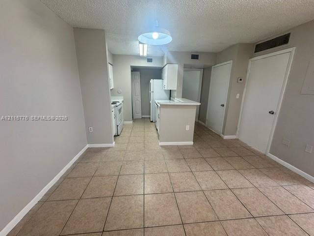 Kitchen featuring a peninsula, white cabinetry, tile flooring, and overhead lighting