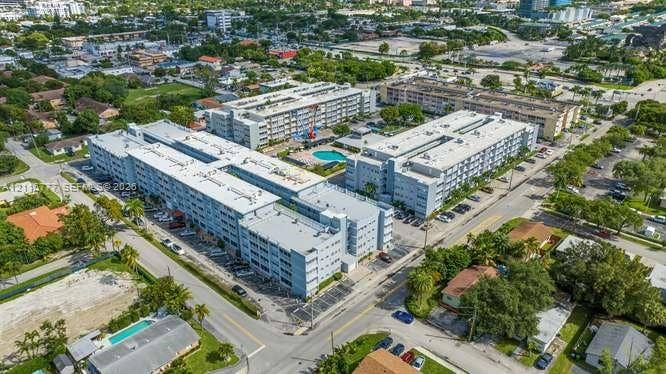 215 SE 3rd Avenue, #501B, Hallandale Beach, FL 33009 Aerial perspective of a multi-story residential complex featuring paved surface parking, a centralized swimming pool, and manicured landscaping
