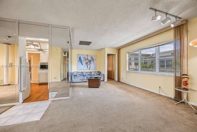 215 SE 3rd Avenue, #501B, Hallandale Beach, FL 33009 Spacious interior featuring full-wall mirrored paneling, large-format windows with track lighting, and a combination of carpet and tile flooring