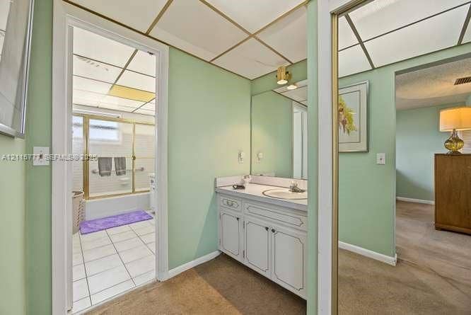 215 SE 3rd Avenue, #501B, Hallandale Beach, FL 33009 Bathroom area featuring a vanity with white cabinetry, a single sink, an integrated mirror, and a drop-in shower enclosure with a glass frame