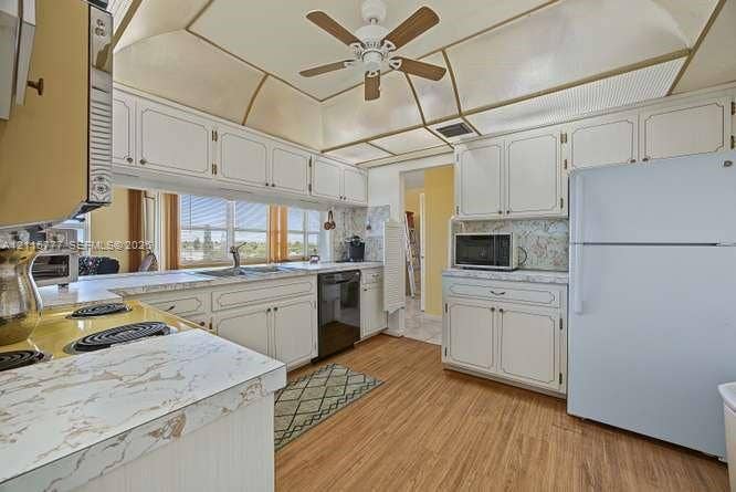 215 SE 3rd Avenue, #501B, Hallandale Beach, FL 33009 Kitchen featuring white cabinetry with decorative trim, wood-finish flooring, tray ceiling with recessed lighting, and stone-finish laminate countertops