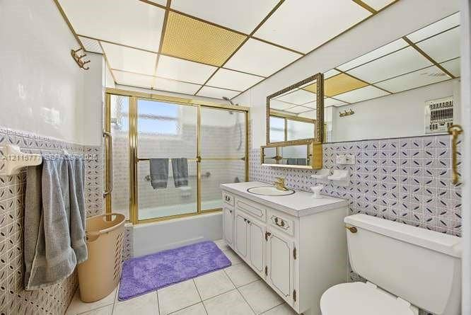 215 SE 3rd Avenue, #501B, Hallandale Beach, FL 33009 Bathroom featuring a vanity with white cabinetry, a composite countertop, and an integrated circular sink, complemented by patterned wall tile, a metal-framed shower enclosure, and a grid-style ceiling panel system