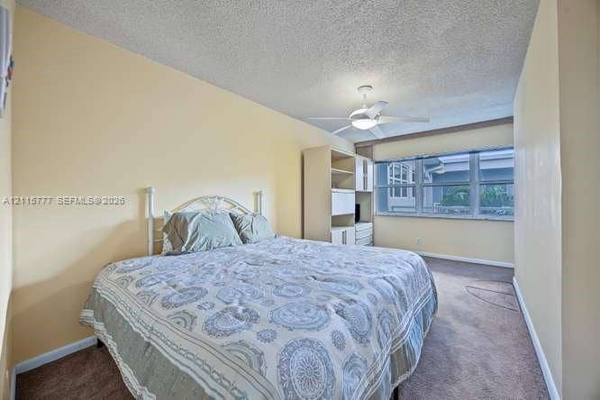 215 SE 3rd Avenue, #501B, Hallandale Beach, FL 33009 Bedroom featuring large windows, neutral wall tones, carpeted flooring, a ceiling fan with integrated lighting, and built-in shelving