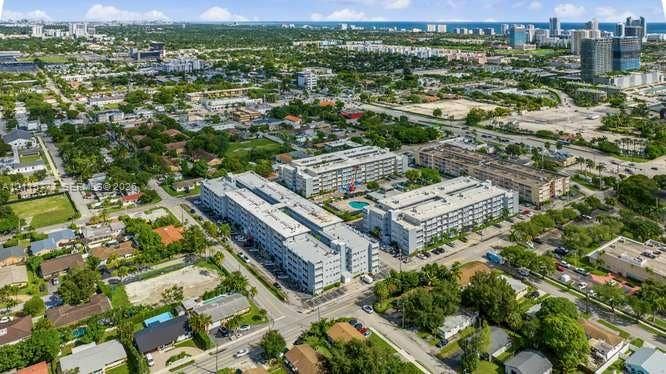 215 SE 3rd Avenue, #501B, Hallandale Beach, FL 33009 Aerial perspective of the property featuring multi-story residential buildings, an exterior swimming pool, surface parking, and mature landscape elements