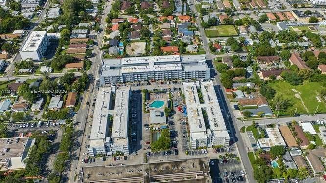215 SE 3rd Avenue, #501B, Hallandale Beach, FL 33009 Aerial perspective of a multi-story residential complex featuring a central outdoor swimming pool, paved surface parking, flat roof architecture, and integrated landscaping