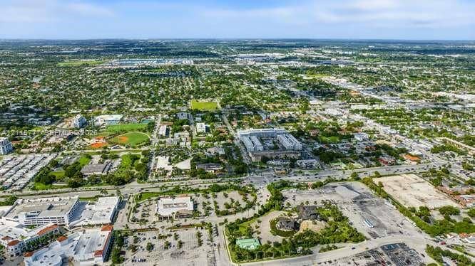 215 SE 3rd Avenue, #501B, Hallandale Beach, FL 33009 Aerial perspective featuring expansive urban infrastructure, multi-level commercial structures, paved parking facilities, and surrounding green space