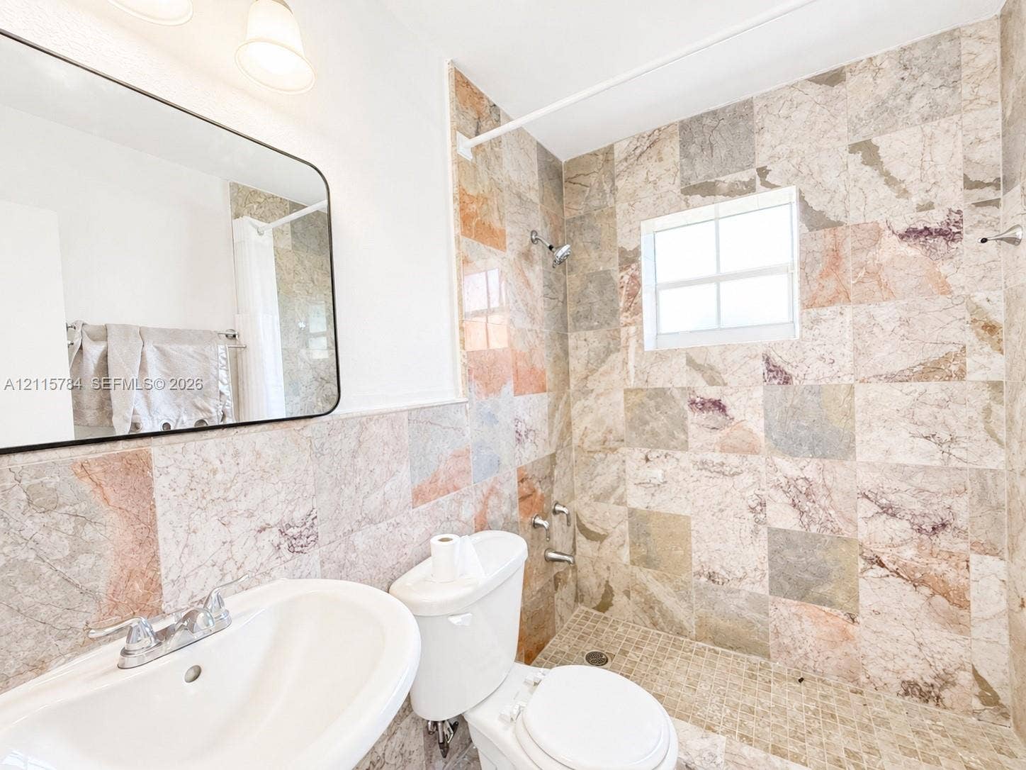 3655 SW 24th Terrace, #1, Miami, Miami, FL 33145 Bathroom featuring floor-to-ceiling stone tile, a pedestal sink, a wall-mounted rectangular mirror, and a walk-in shower with stone mosaic flooring