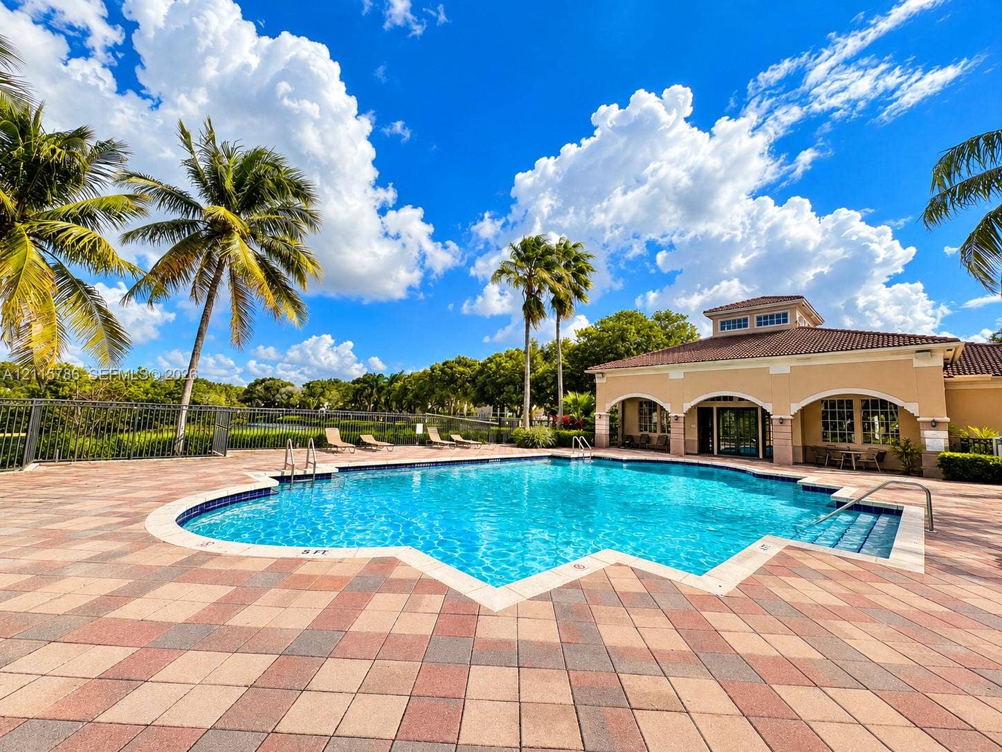 2494 Centergate Drive, #202, Miramar, Miramar, FL 33025 Swimming pool featuring a stone paver deck, integrated step entry, metal handrails, and architectural clubhouse building