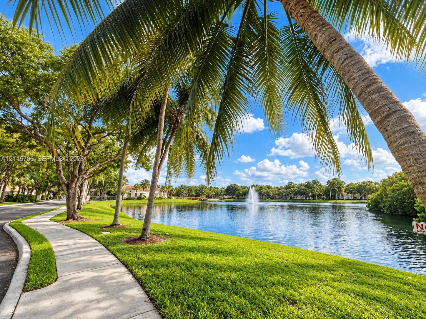 2494 Centergate Drive, #202, Miramar, Miramar, FL 33025 Concrete walking path, expansive waterfront, central fountain, mature palm trees, and manicured green space