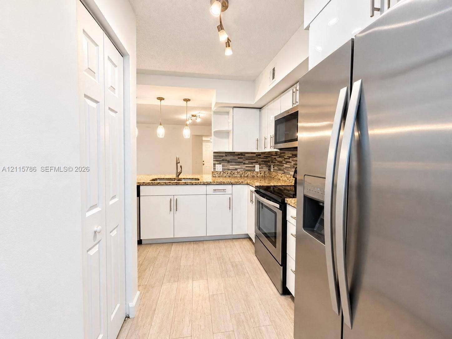 2494 Centergate Drive, #202, Miramar, Miramar, FL 33025 Kitchen featuring white cabinetry, stone-finish countertops, stainless steel appliances, multi-toned tile backsplash, and wood-finish flooring