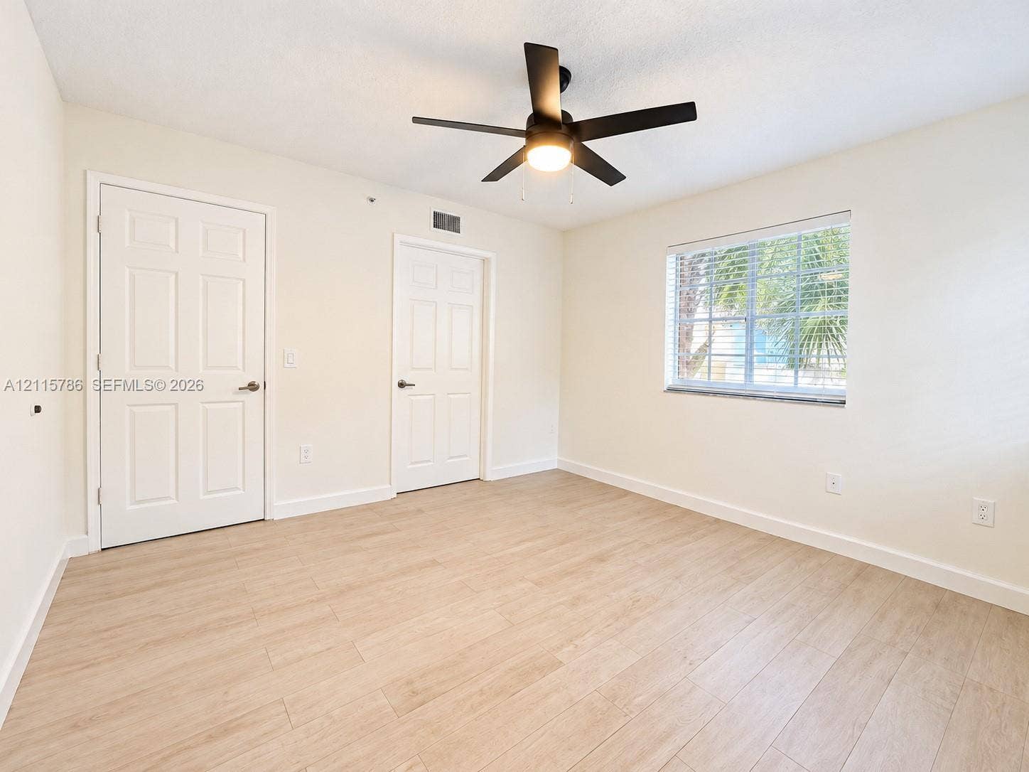 2494 Centergate Drive, #202, Miramar, Miramar, FL 33025 Interior space featuring wood-finish flooring, a matte black ceiling fan with an integrated light fixture, and two six-panel doors
