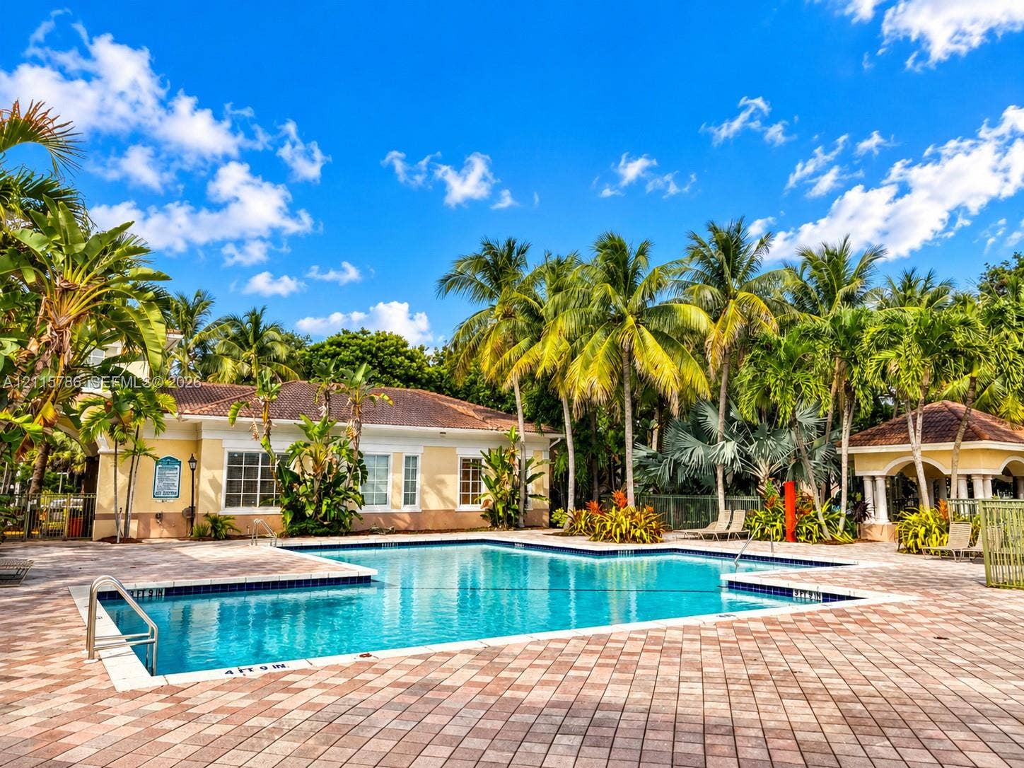 2494 Centergate Drive, #202, Miramar, Miramar, FL 33025 Community swimming pool featuring a brick paver deck, metal pool ladder, built-in pavilion, and mature palm tree landscaping