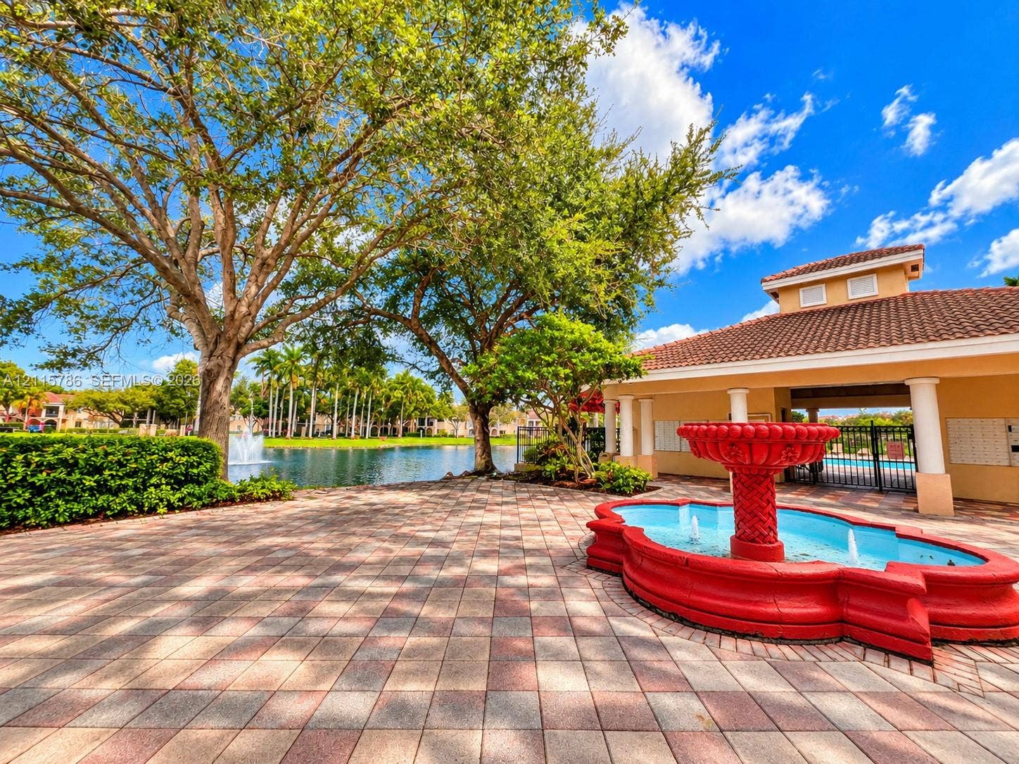 2494 Centergate Drive, #202, Miramar, Miramar, FL 33025 Paved courtyard featuring a decorative fountain, mature landscaping, and waterfront scenery
