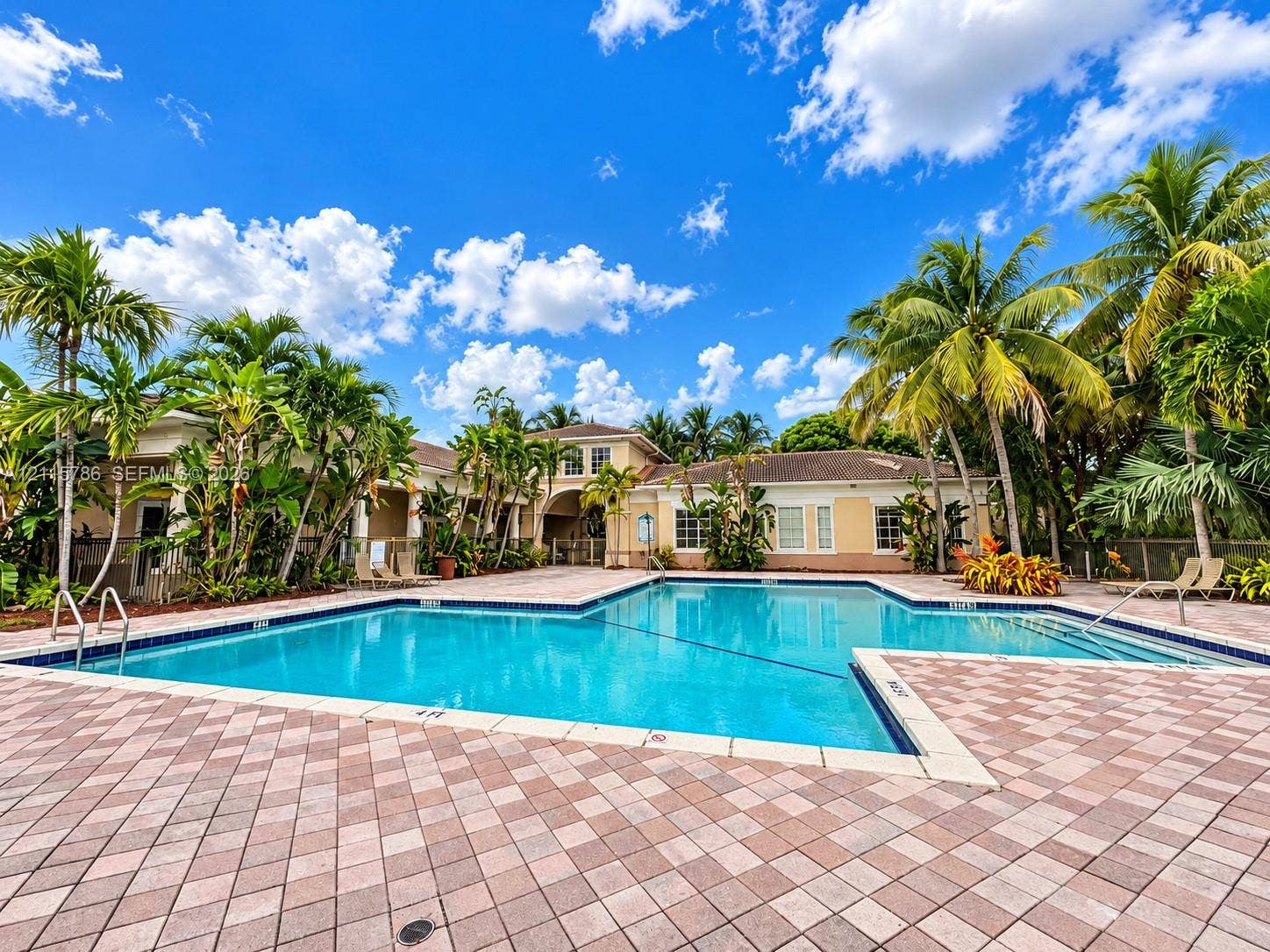 2494 Centergate Drive, #202, Miramar, Miramar, FL 33025 In-ground swimming pool featuring a tiled deck, stone-paver surround, metal handrails, and tropical landscaping