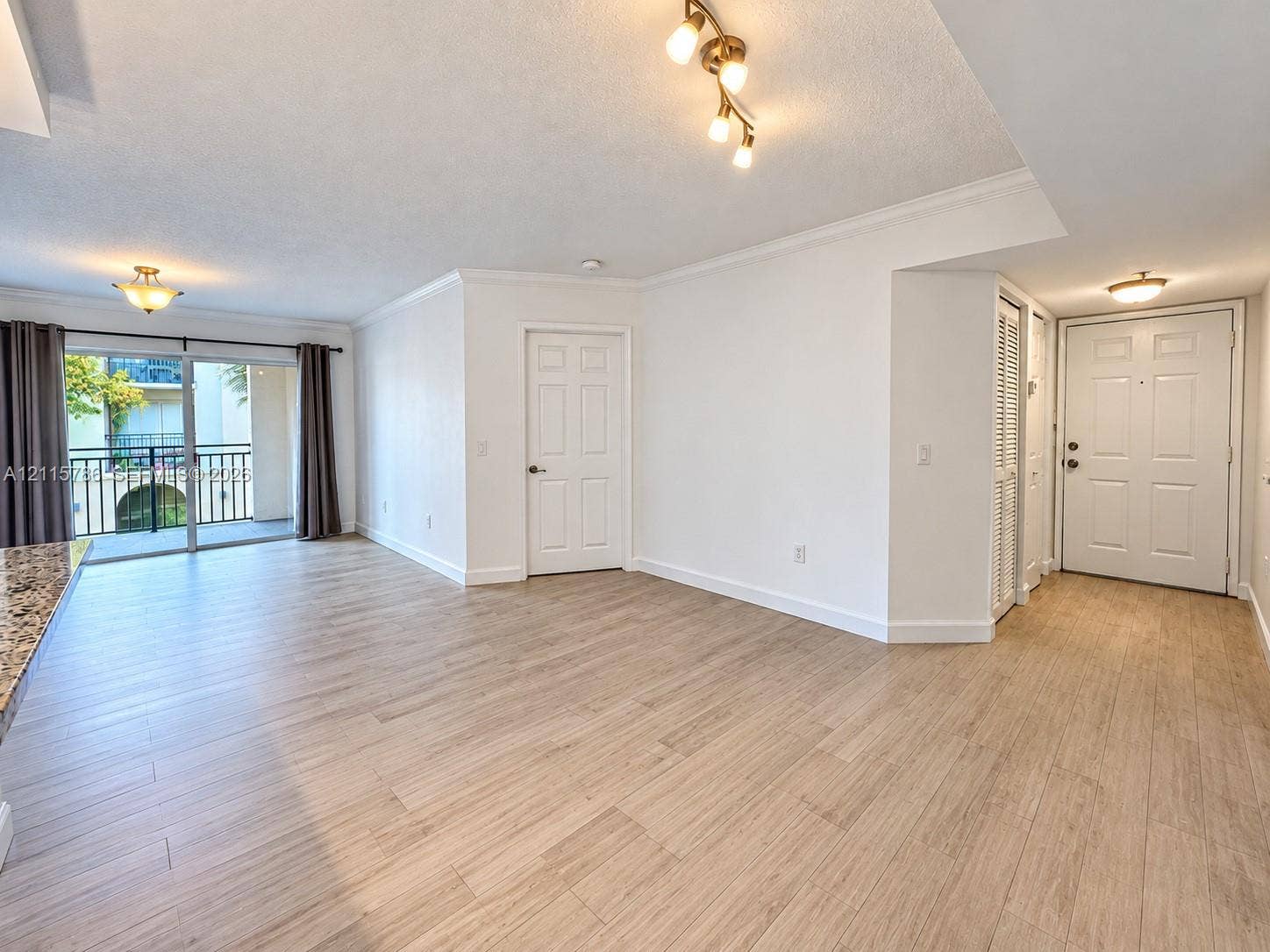 2494 Centergate Drive, #202, Miramar, Miramar, FL 33025 Wood-finish flooring, sliding glass patio door, multi-light flush-mount ceiling fixtures, crown molding, and six-panel interior doors