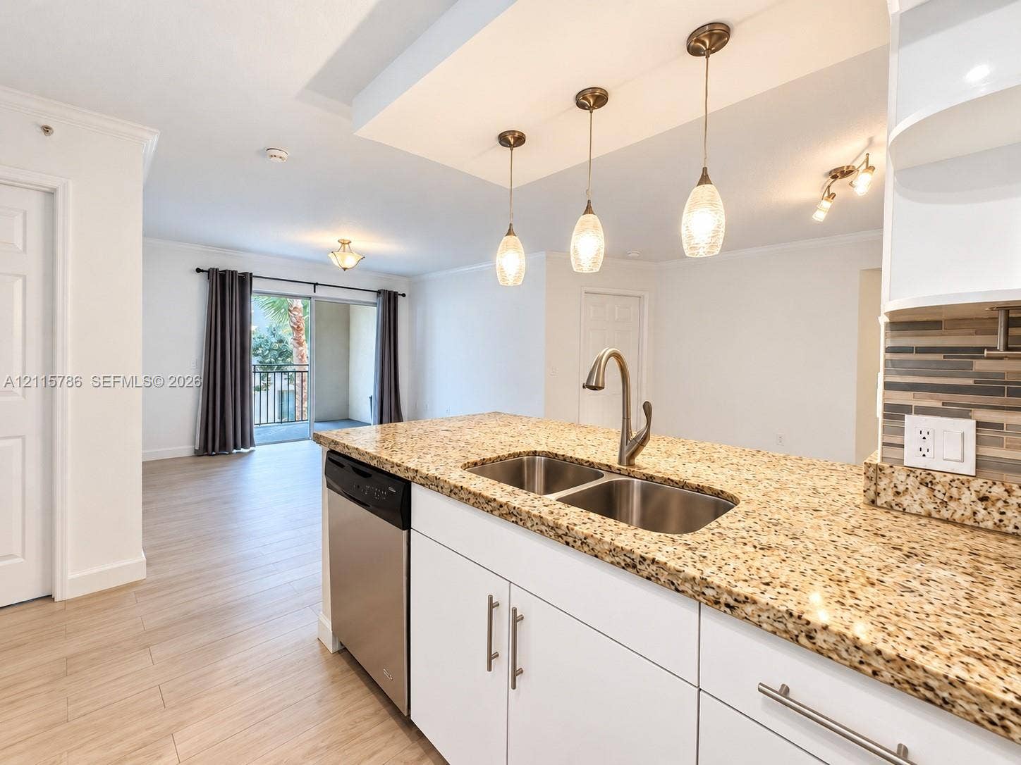 2494 Centergate Drive, #202, Miramar, Miramar, FL 33025 Kitchen featuring an island with stone-surface countertops, dual-basin stainless steel sink, modern pendant lighting, white cabinetry with metallic hardware, and wood-finish flooring