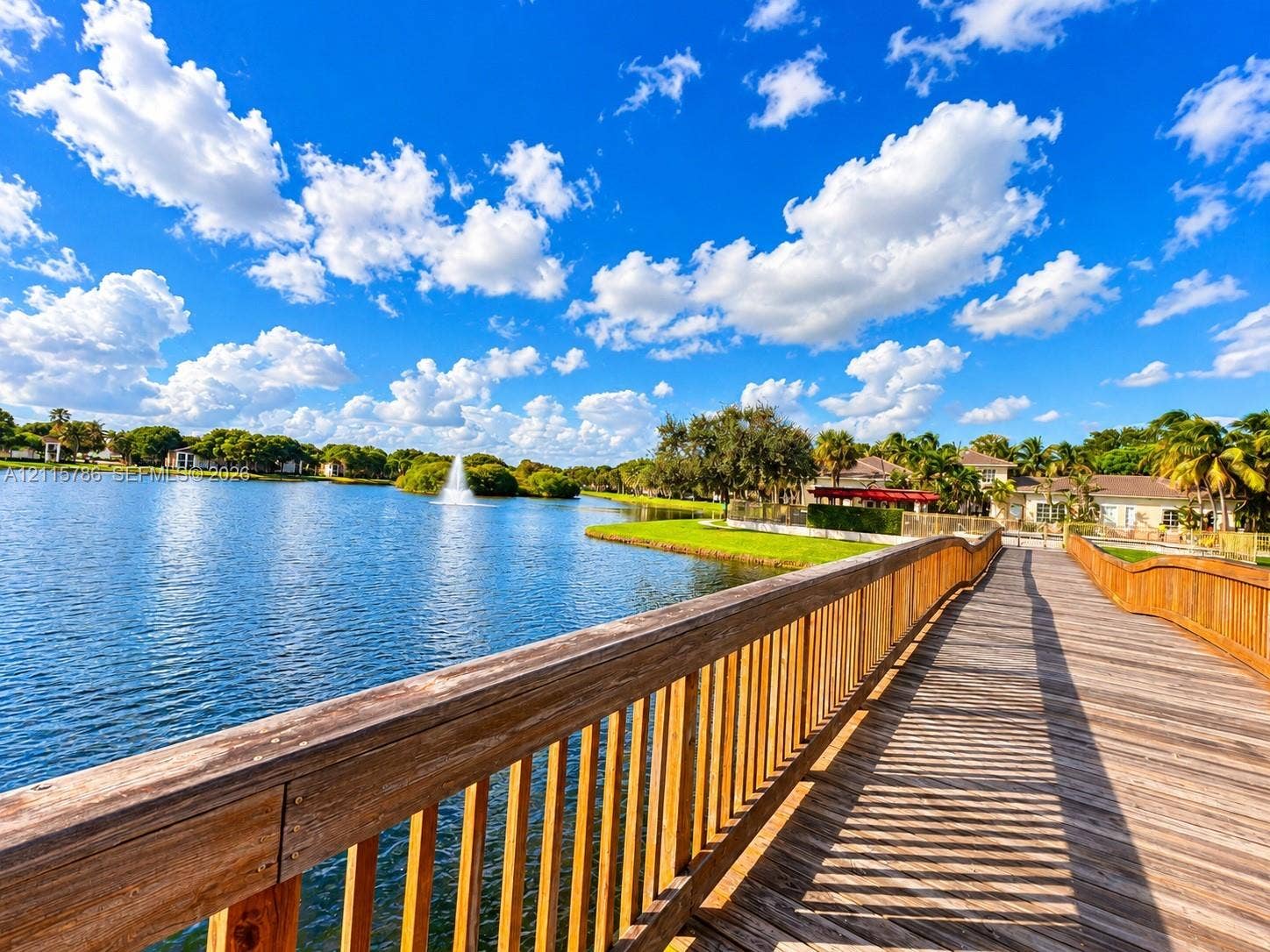 2494 Centergate Drive, #202, Miramar, Miramar, FL 33025 Wood-plank pedestrian bridge featuring natural wood railings, water fountain feature, and perimeter landscaping