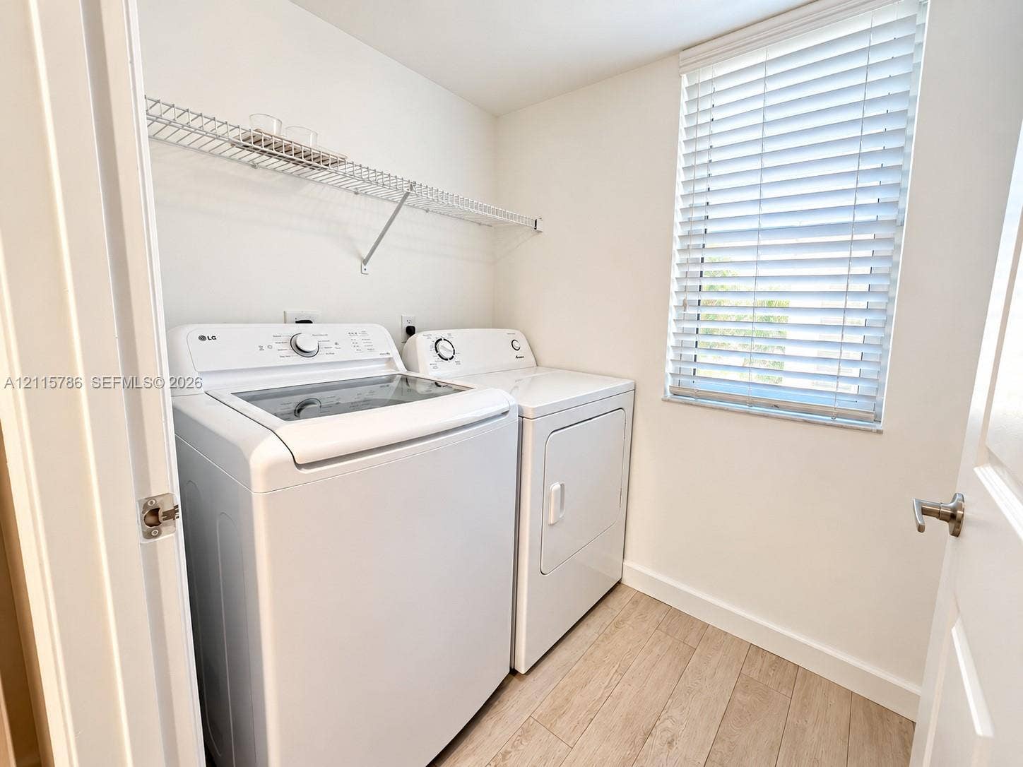 2494 Centergate Drive, #202, Miramar, Miramar, FL 33025 Utility room featuring wood-finish flooring, white walls, horizontal window blinds, and integrated wire shelving