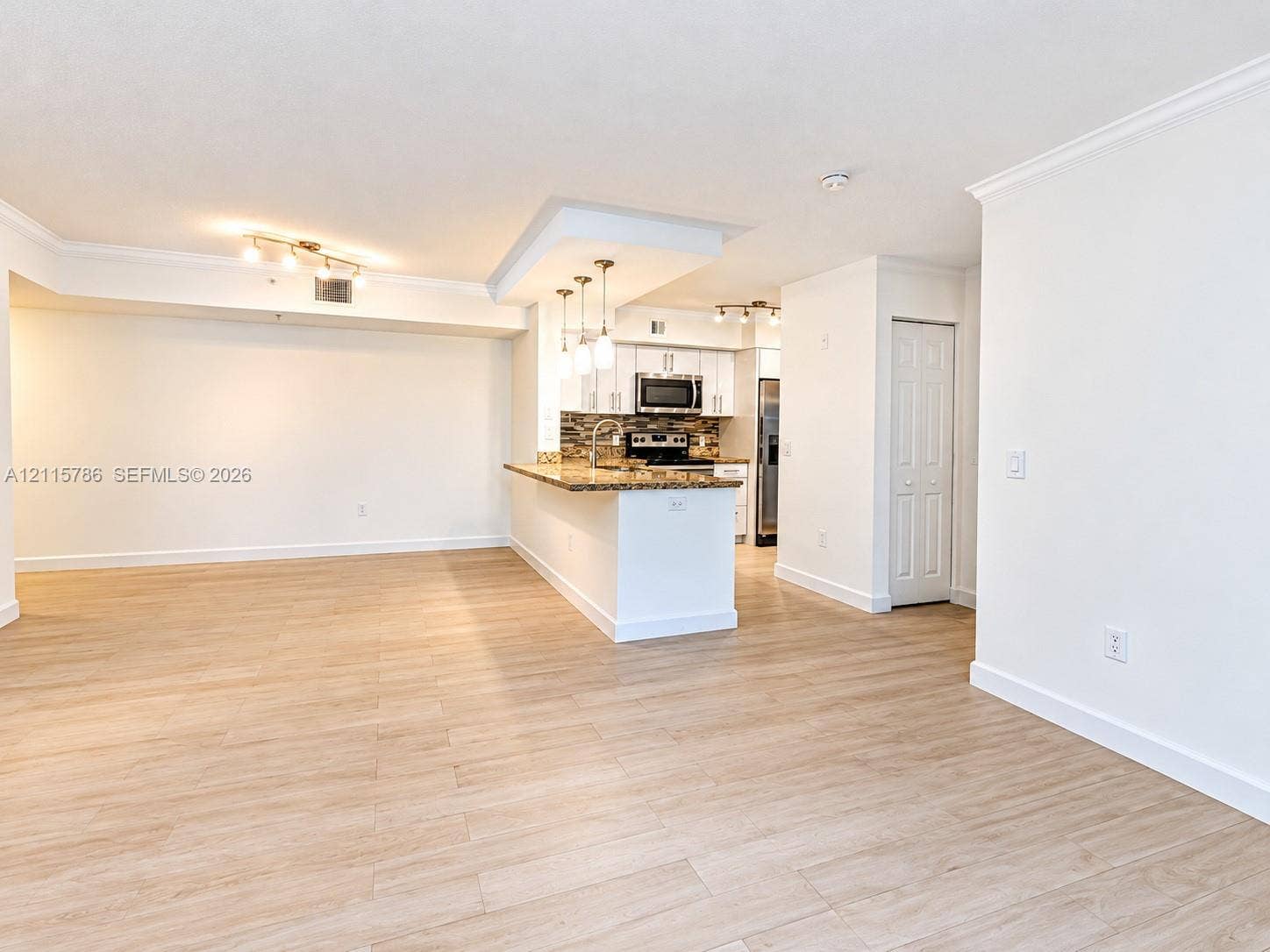 2494 Centergate Drive, #202, Miramar, Miramar, FL 33025 Kitchen featuring white cabinetry, stone-surface countertops, stone-tile backsplash, and stainless-steel appliances, complemented by wood-finish flooring throughout the space