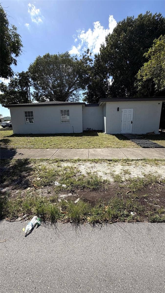 16220 NW 28th Place, Miami Gardens, FL 33054 Single-story exterior featuring light-toned smooth siding, a low-slope roofline, and multi-pane windows